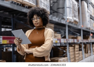 Young African American female looking at camera working in warehouse using digital tablet checking inspection on shelves.woman worker check stock inspecting in storage logistic factory. - Powered by Shutterstock