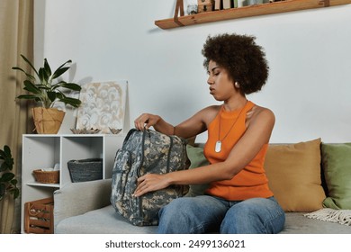 A young African American female soldier packs her backpack in a warm living room filled with personal touches. - Powered by Shutterstock