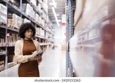 Young African American female working in warehouse using digital tablet checking inspection on shelves.woman worker check stock inspecting in storage logistic factory.