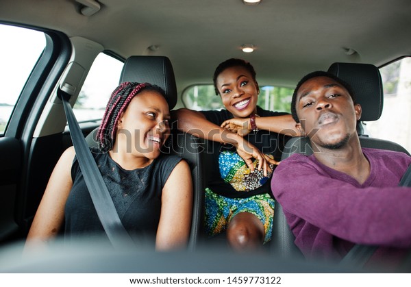 Young\
african american friends sitting inside a\
car.
