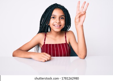 Young African American Girl Child With Braids Wearing Casual Clothes Sitting On The Table Showing And Pointing Up With Fingers Number Three While Smiling Confident And Happy. 