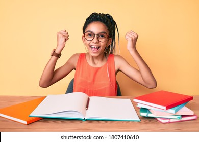 Young african american girl child with braids studying for school exam screaming proud, celebrating victory and success very excited with raised arms  - Powered by Shutterstock