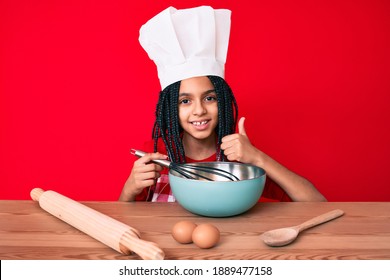 Young African American Girl Child With Braids Cooking Using Baker Whisk Smiling Happy And Positive, Thumb Up Doing Excellent And Approval Sign 