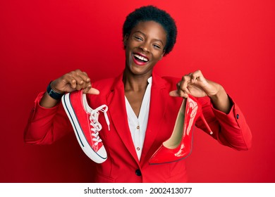 Young African American Girl Choosing High Heel Shoes And Sneakers Smiling And Laughing Hard Out Loud Because Funny Crazy Joke. 