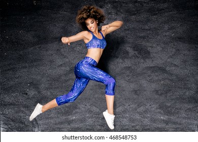 Young african american girl dancing, jumping. Studio shot. Fit body. Happiness.