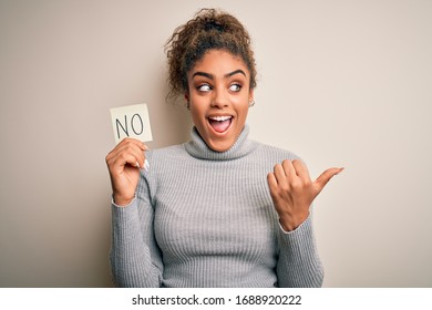 Young African American Girl Holding Reminder Paper With No Word Negative Message Pointing And Showing With Thumb Up To The Side With Happy Face Smiling