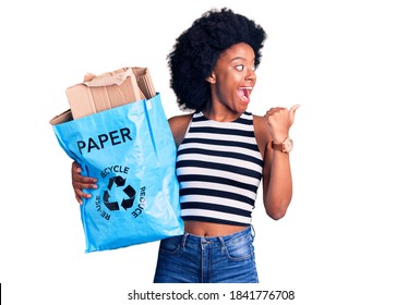 Young African American Girl Holding Recycling Bag With Paper And Cardboard Pointing Thumb Up To The Side Smiling Happy With Open Mouth 