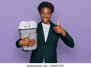 Young African American Girl Holding Paper Bin Full Of Crumpled Papers Smiling Happy And Positive, Thumb Up Doing Excellent And Approval Sign 