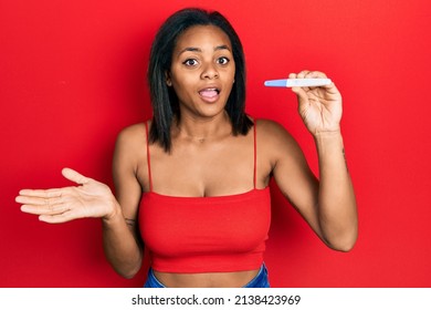 Young african american girl holding pregnancy test result celebrating achievement with happy smile and winner expression with raised hand 
