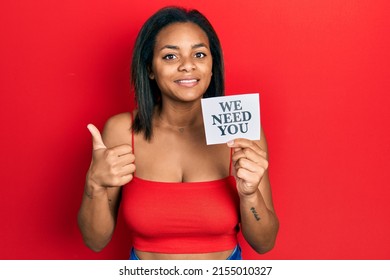 Young African American Girl Holding We Need You Paper Smiling Happy And Positive, Thumb Up Doing Excellent And Approval Sign 