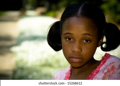 A Young African American Girl Looks Sad In The Park.