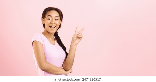 A young African American girl is making a peace sign gesture. She smiles as she holds up her fingers in the iconic symbol of peace and harmony, copy space - Powered by Shutterstock