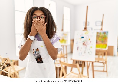 Young African American Girl Painting At Art Studio Shocked Covering Mouth With Hands For Mistake. Secret Concept. 