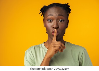 Young African American Girl Showing You Shh Sign In Yellow Studio