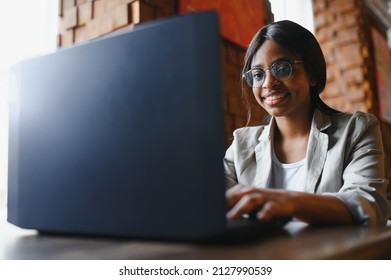 Young African American Girl Sitting In Restaurant And Typing On Her Laptop. Pretty Girl Working On Computer At Cafe.