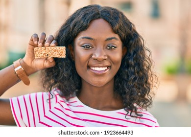 Young African American Girl Smiling Happy Holding Cereal Protein Bar At The City.