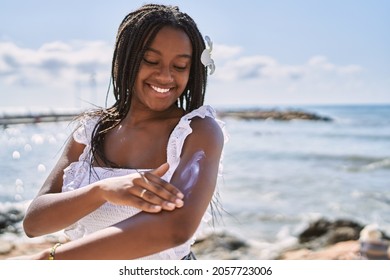 Young african american girl smiling happy using sunscreen lotion at the beach. - Powered by Shutterstock