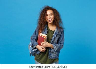 Young African American Girl Teen Student In Denim Clothes, Backpack Hold Books Isolated On Blue Background Studio Portrait. Education In High School University College Concept. Mock Up Copy Space