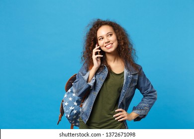 Young African American Girl Teen Student In Denim Clothes, Backpack Hold Phone Isolated On Blue Background Studio Portrait. Education In High School University College Concept. Mock Up Copy Space