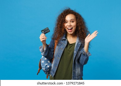 Young african american girl teen student in denim clothes backpack hold credit card isolated on blue background studio portrait. Education in high school university college concept Mock up copy space