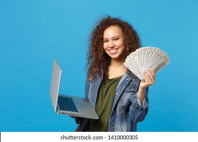 Young African American Girl Teen Student In Denim Clothes, Backpack Hold Pc, Fan Of Cash Money Isolated On Blue Background. Education In High School University College Concept. Mock Up Copy Space.