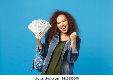 Young african american girl teen student in denim clothes, backpack hold money isolated on blue background studio portrait. Education in high school university college concept. Mock up copy space