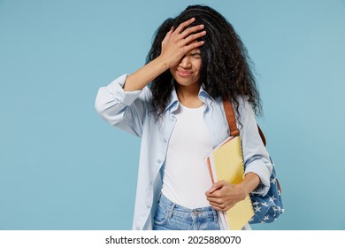 Young african american girl teen student in denim clothes backpack hold books do facepalm epic fail mistaken omg gesture isolated on blue background Education in high school university college concept