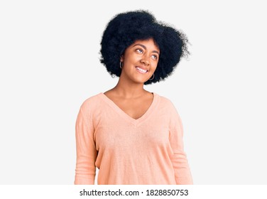 Young african american girl wearing casual clothes looking away to side with smile on face, natural expression. laughing confident. 