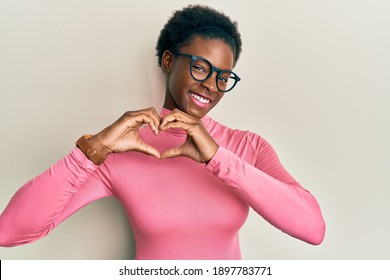 Young african american girl wearing casual clothes and glasses smiling in love doing heart symbol shape with hands. romantic concept. 