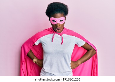 Young African American Girl Wearing Super Hero Costume And Medical Mask Afraid And Shocked With Surprise And Amazed Expression, Fear And Excited Face. 