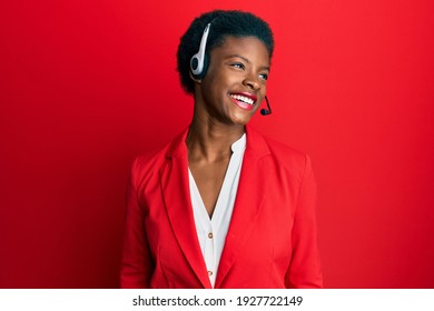 Young african american girl wearing call center agent headset looking away to side with smile on face, natural expression. laughing confident. 