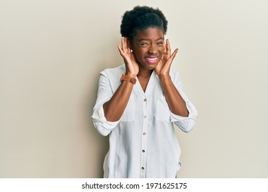 Young african american girl wearing casual clothes trying to hear both hands on ear gesture, curious for gossip. hearing problem, deaf 