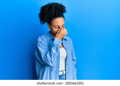 Young african american girl wearing casual clothes tired rubbing nose and eyes feeling fatigue and headache. stress and frustration concept.  - Shutterstock ID 2003662301