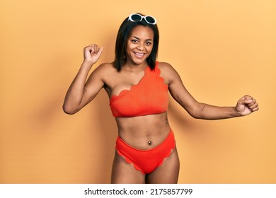 Young african american girl wearing bikini dancing happy and cheerful, smiling moving casual and confident listening to music 