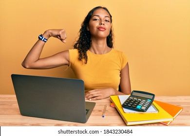 Young African American Girl Working At The Office With Laptop And Calculator Strong Person Showing Arm Muscle, Confident And Proud Of Power 