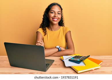 Young African American Girl Working At The Office With Laptop And Calculator Happy Face Smiling With Crossed Arms Looking At The Camera. Positive Person. 