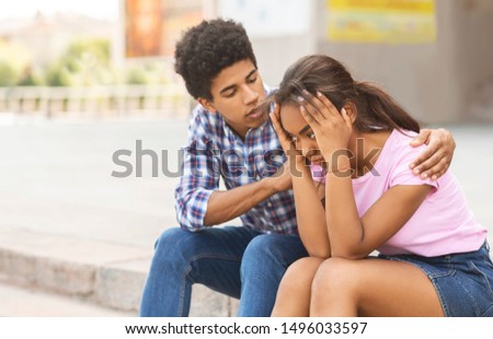 Young african american guy comforting his sad girlfriend after arguing on public.