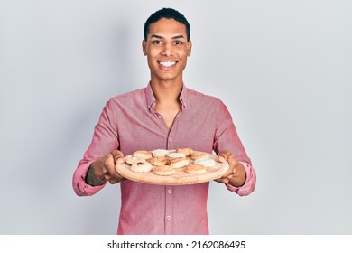 Young African American Guy Holding Tray With Cake Sweets Smiling With A Happy And Cool Smile On Face. Showing Teeth. 