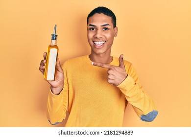 Young African American Guy Holding Olive Oil Can Smiling Happy Pointing With Hand And Finger 