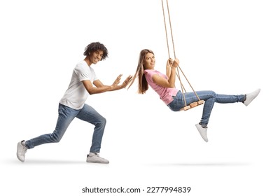 Young african american guy pushing a caucasian female on a swing isolated on white background