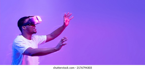 Young African American Guy Touching Air While Having Virtual Reality Experience In VR Glasses Headset, Black Man Enjoying Video Games, Standing In Vivid Neon Light Over Purple Background, Collage