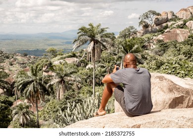 young African American Hiker looking mountain and enjoying sunrise using smartphone