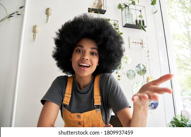 Young African American hipster woman with Afro hair looking at webcam talking to camera with friend online sitting at cafe table making video call, virtual chat, recording blog, headshot portrait.