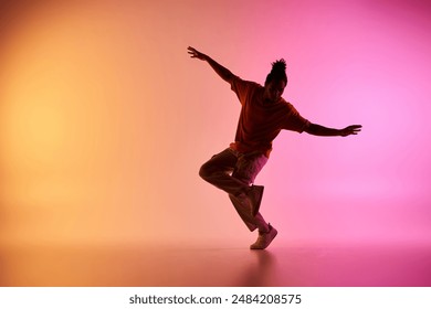 A young African American male dancer executes a move in a vibrant studio setting with a colorful gradient background.