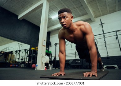 Young African American Male Doing Push-ups In The Gym. Mixed Race, Male Personal Trainer Doing Cross Fit Indoors. High Quality Photo