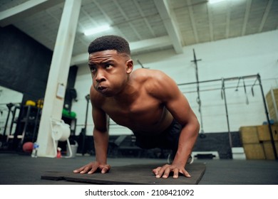 Young African American Male Doing Push-ups In The Gym. Mixed Race, Male Personal Trainer Doing Cross Fit Indoors. High Quality Photo