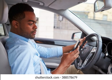 Young African American Male Driver Using Phone, In Car View