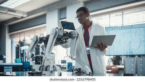 Young African American Male Engineer Testing Industrial Programmable Robot Animal in a Factory Development Workshop. Black Researcher in a Lab Coat Developing AI Pet Prototype, Using Laptop - Powered by Shutterstock