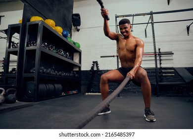 Young African American Male Exercising Inside A Gym. Mixed Race Male Personal Trainer Using Rope To Strengthen His Arms. High Quality Photo