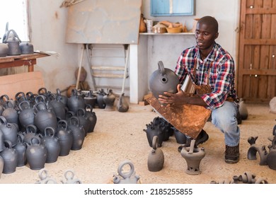 Young African American male hobbyist engaged in stoneware production in pottery workshop, looking at products - Shutterstock ID 2185255855